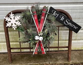 old metal headboard with wreath, decorative skiis and snowflake and Let It Snow sign