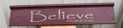 Red wooden sign that says Believe in the Spirit of Christmas