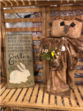 Wooden sign that has the "here cmes Peter cottontail rhyme on it and a primitive bunny with flowers next to it