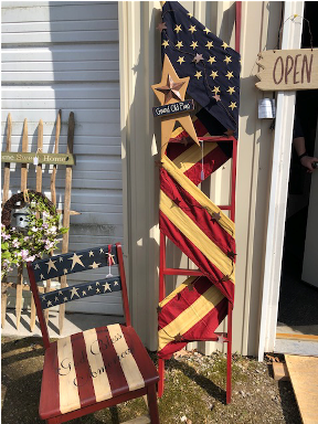 Wooden ladder with flag wrapped around it and star on top. Wood chair painted in Americana theme.